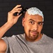 Closeup of man shaving his head with shaving cream on his head